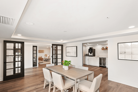 a dining area with a wooden table and white chairs