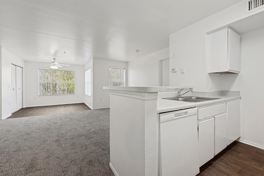 A white kitchen with a sink and a window.