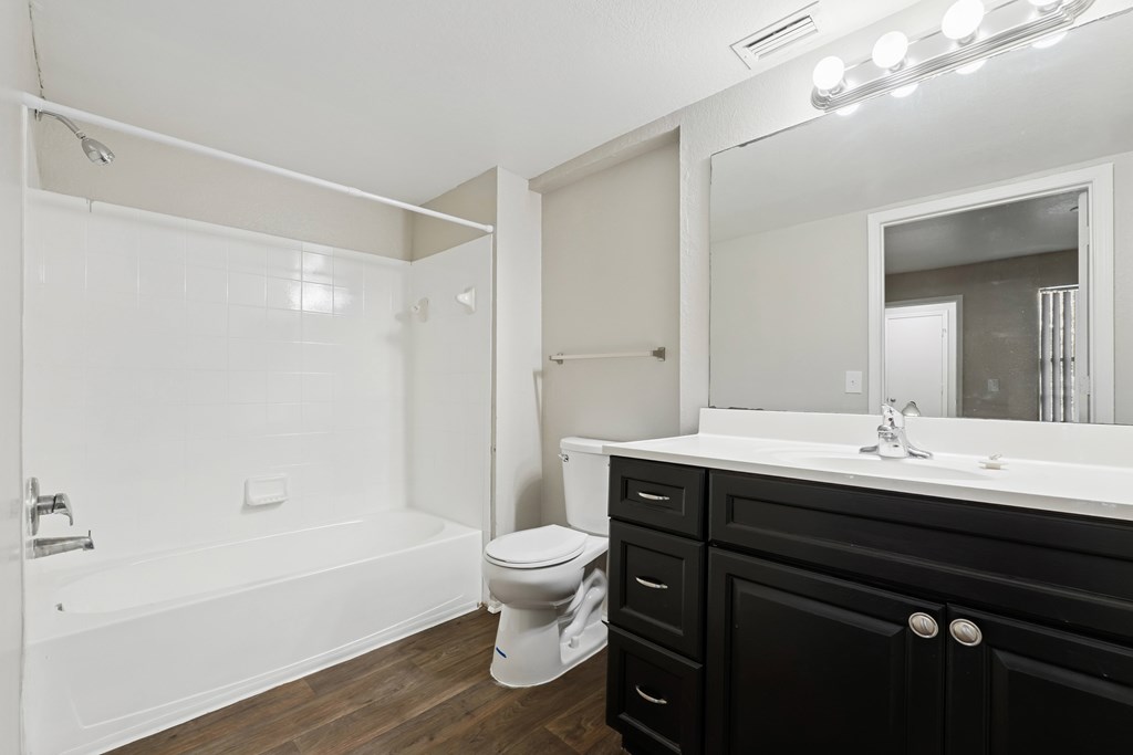 A white bathroom with black drawers and a white toilet.