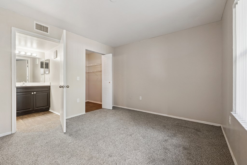 A spacious room with a carpeted floor and a doorway leading to another room.
