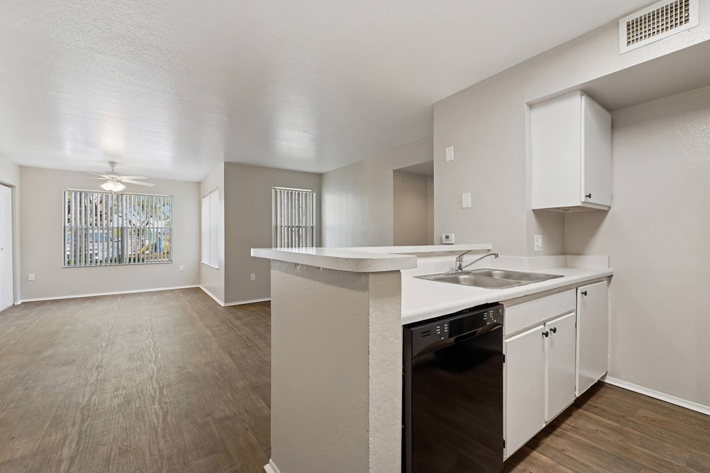 A kitchen with a black dishwasher and white cabinets.