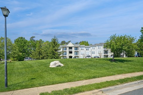 A grassy area with a building in the background and a lamp post on the left.