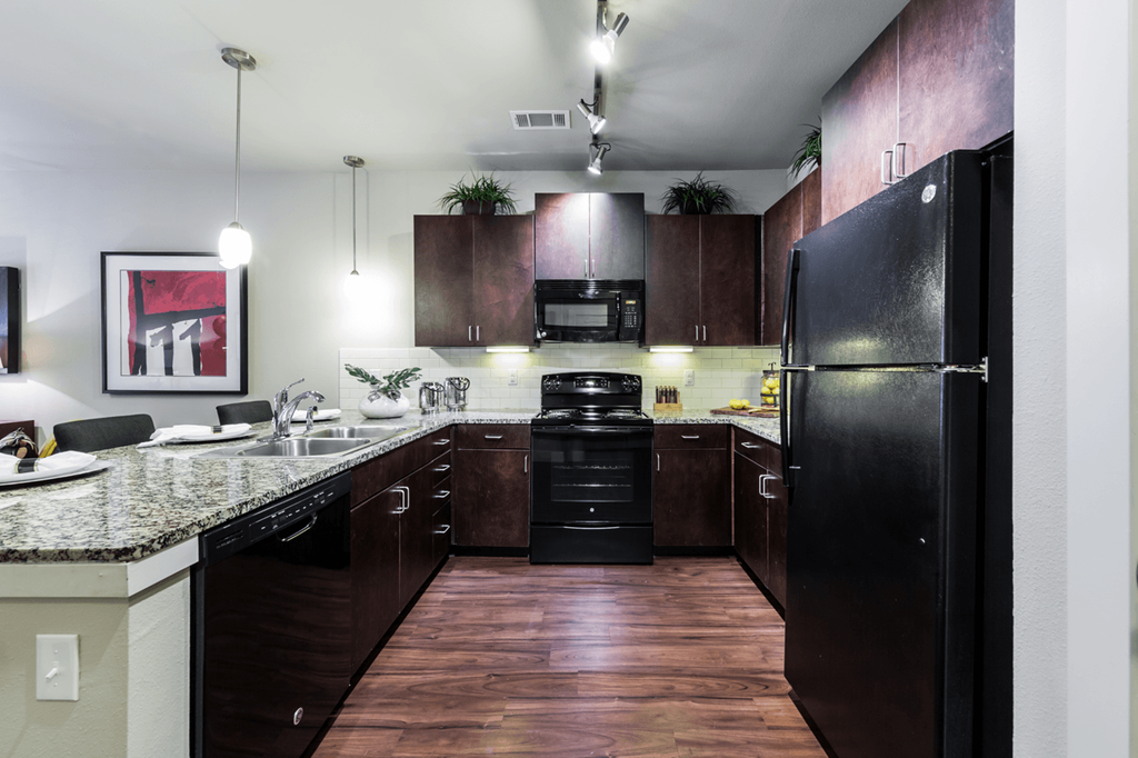 a kitchen with dark wood cabinetry and granite countertops