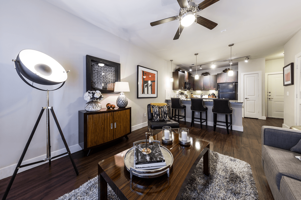 a living room and kitchen area with a ceiling fan and hardwood flooring