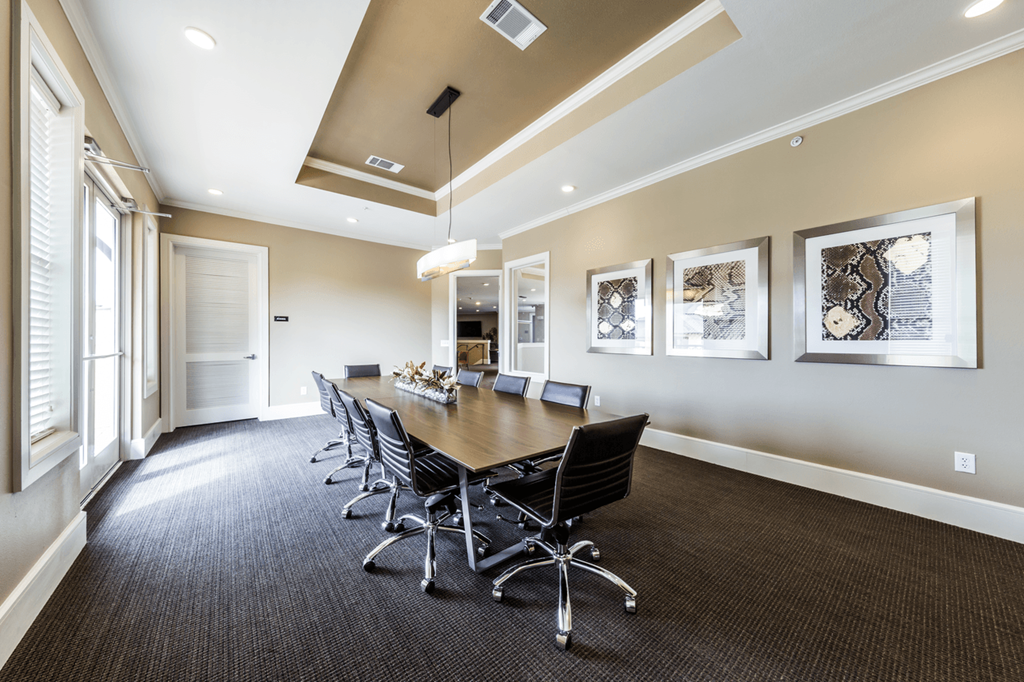 a conference room with a long wooden table and black chairs