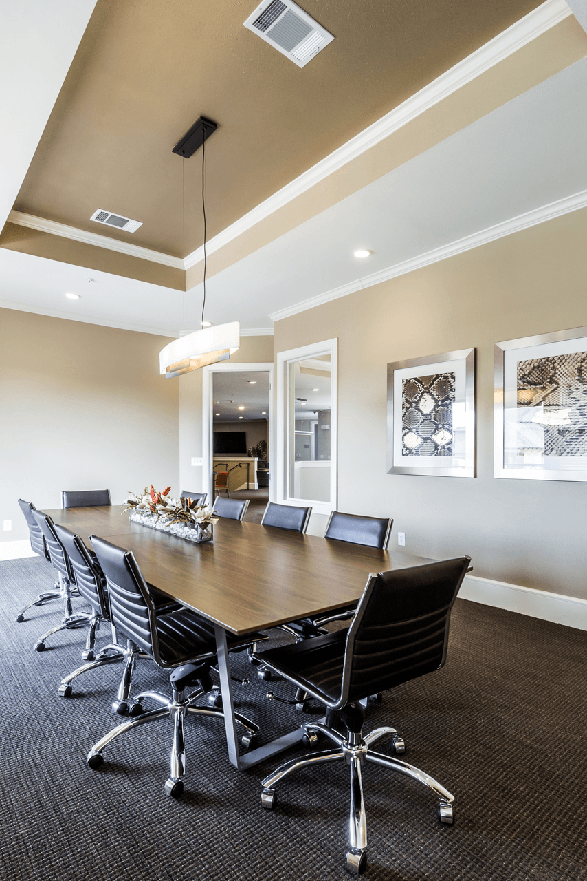 a conference room with a long wooden table and black chairs