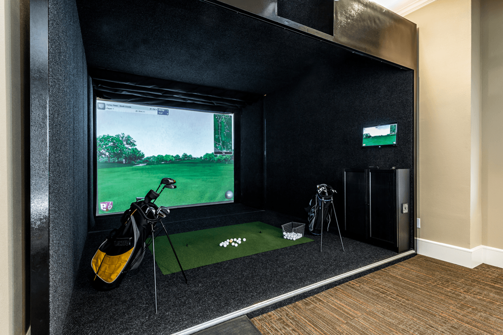 a room with a golf simulator and a large screen tv