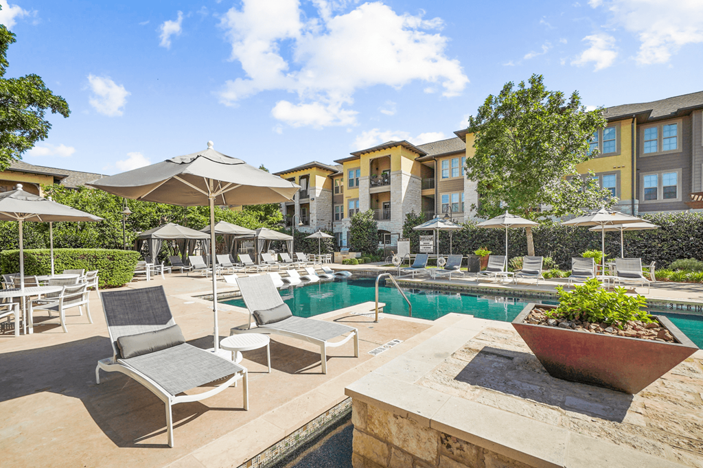 a swimming pool with lounge chairs and umbrellas