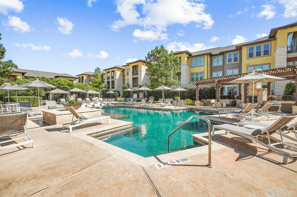 a swimming pool with lounge chairs and umbrellas in front of a building