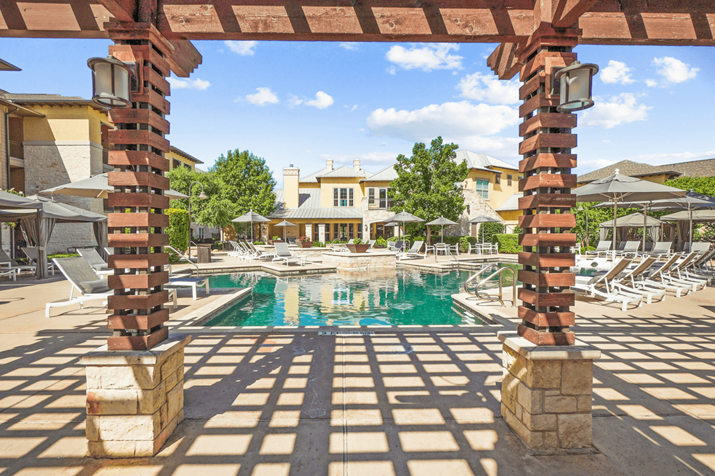 a pool with lounge chairs and umbrellas at the enclave at woodbridge apartments in sugar