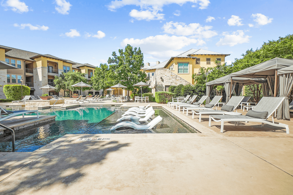 a resort style pool with lounge chairs and umbrellas