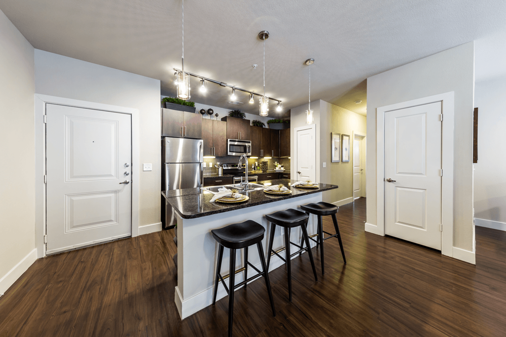 a kitchen with a large island with a breakfast bar and three stools