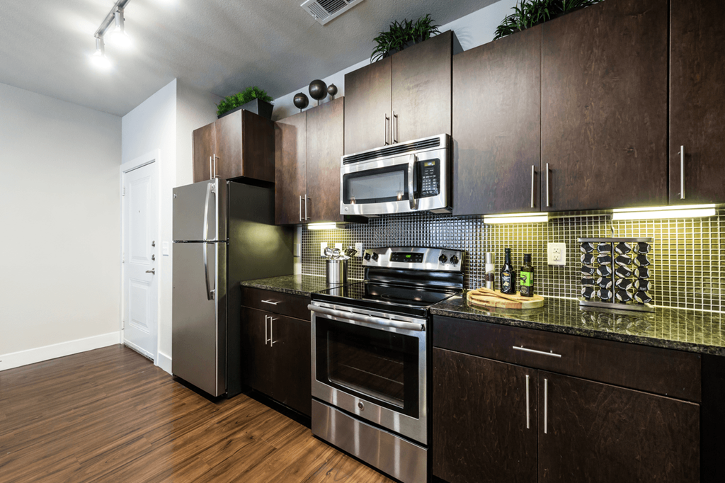 a kitchen with dark wood cabinets and stainless steel appliances