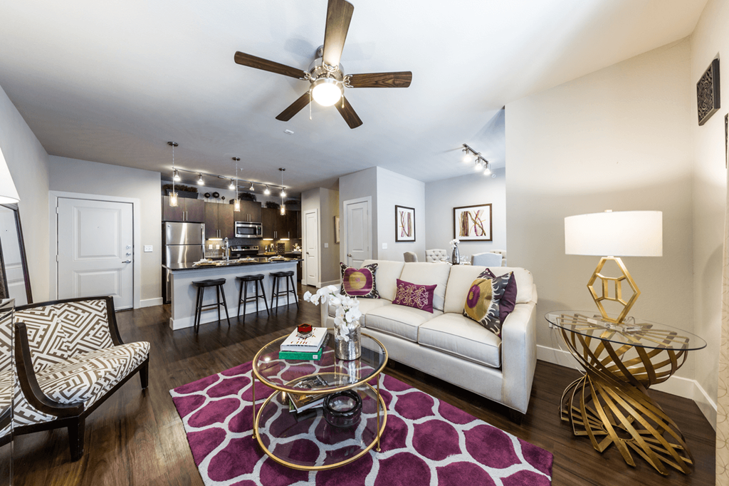 a living room with a ceiling fan and a glass coffee table