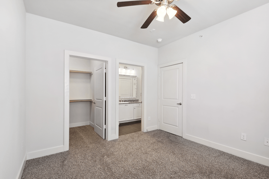 a bedroom with white walls and a ceiling fan