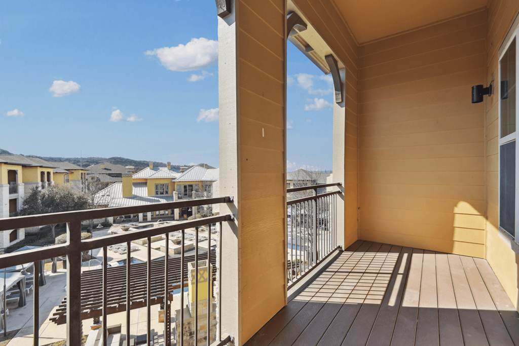 the view from the balcony of a home with yellow walls and a wooden deck