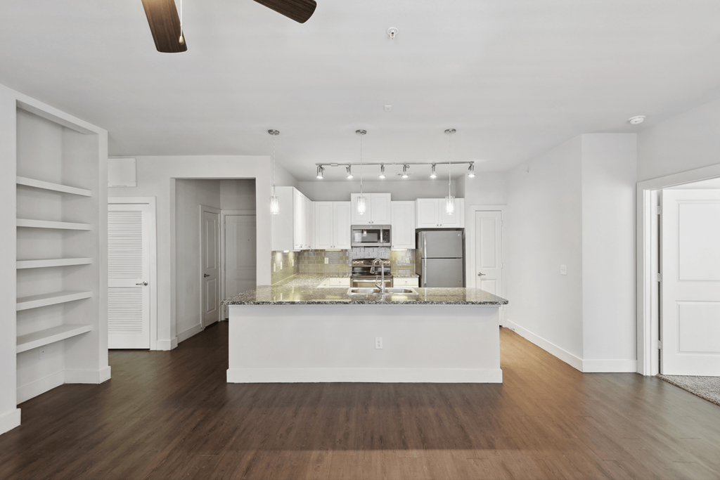 a kitchen with white cabinets and a marble counter top