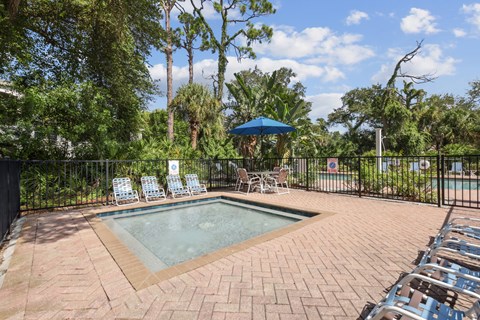 A pool surrounded by chairs and trees.