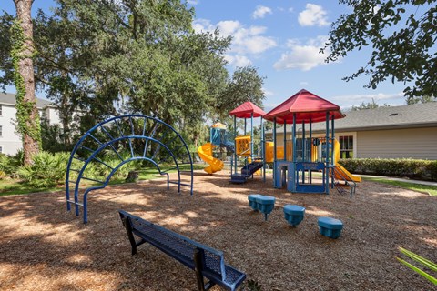 A playground with a red canopy and blue and yellow play equipment.
