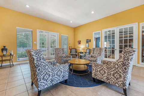 A living room with leopard print chairs and a blue rug.