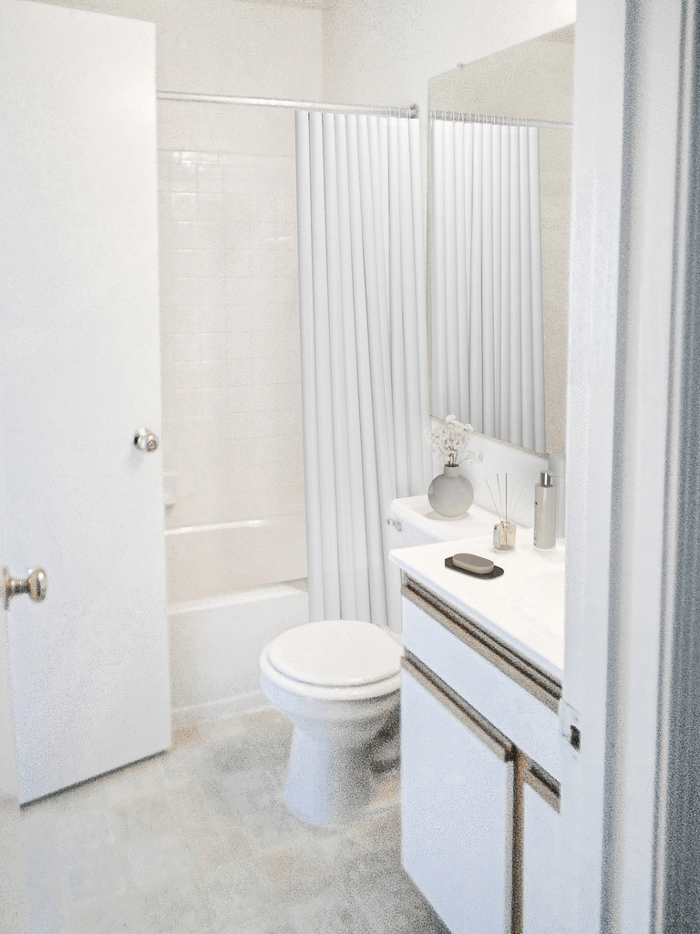 Bathroom with vinyl style flooring, toilet, vanity, and a shower tub combo. Virtually staged with shower curtain, flower on toilet base, and soap on the countertop.