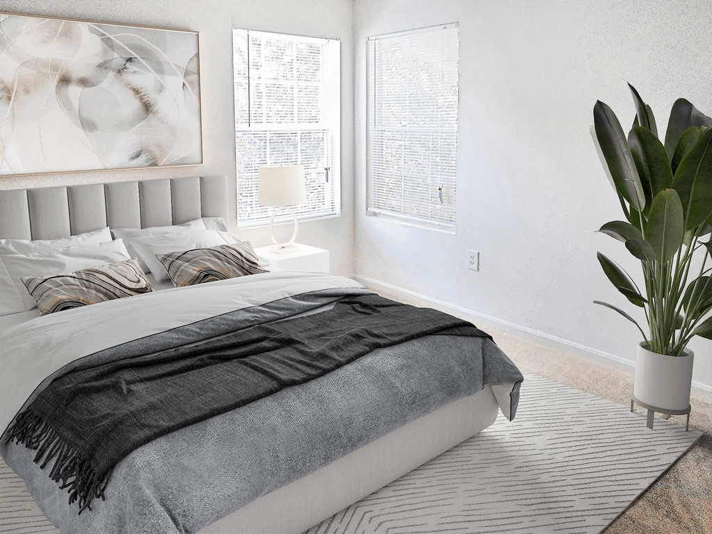 Bedroom with two windows, white walls and beige carpet virtually staged with a bed, wall art, indoor standing plant and designer rug