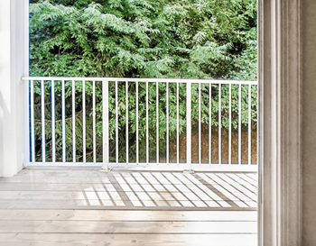 Balcony with wood flooring and white railing overlooking native landscape