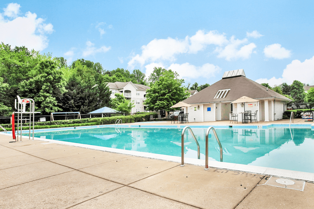 Pool area with tanning chairs on the deck facing leasing office and playground