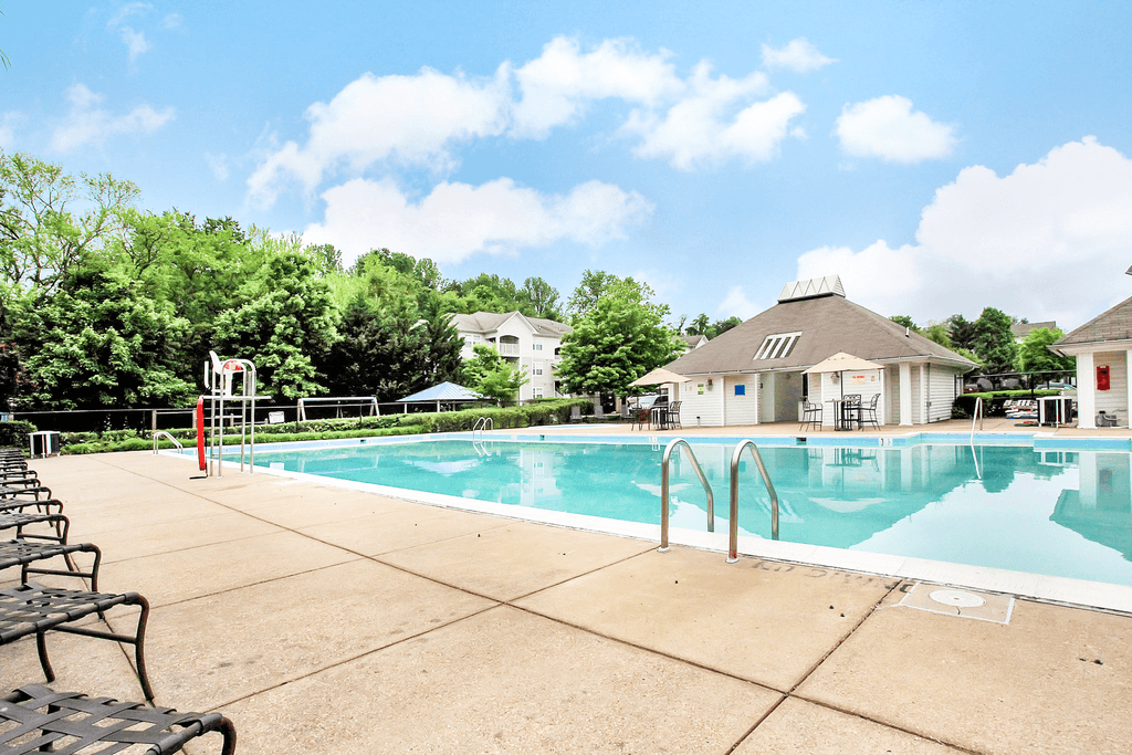 Pool area with tanning chairs on the deck facing leasing office and playground