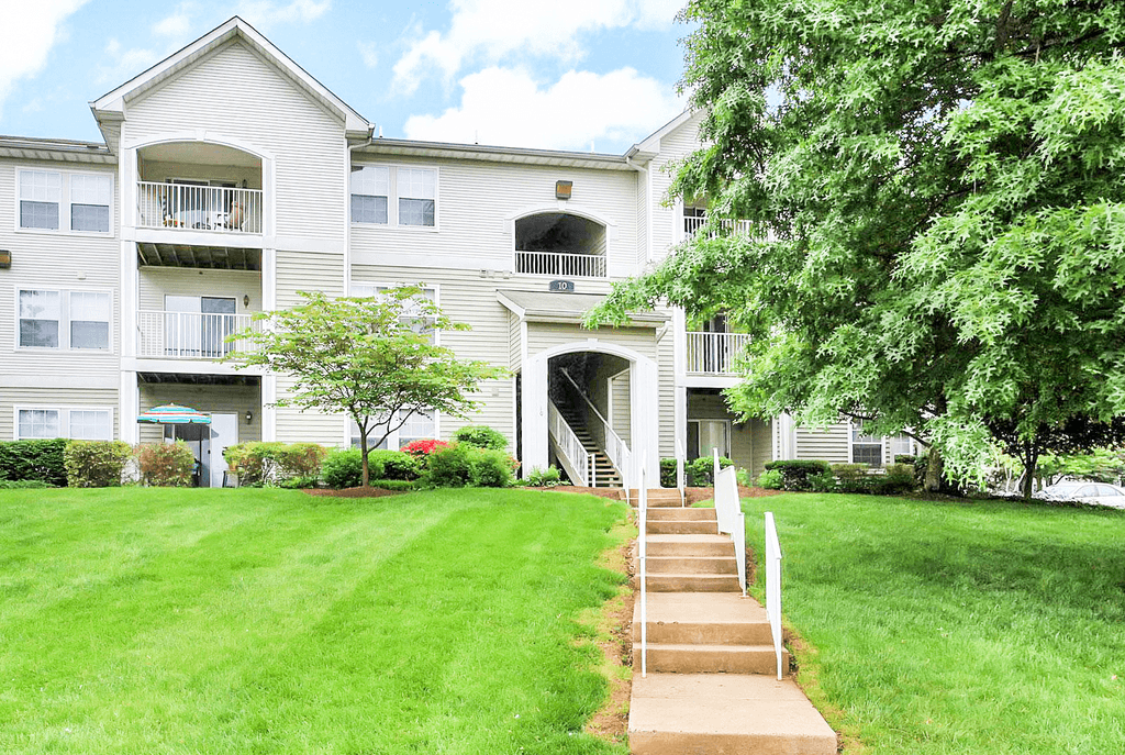 Exterior of buildings with grass and trees and sidewalk leading into community