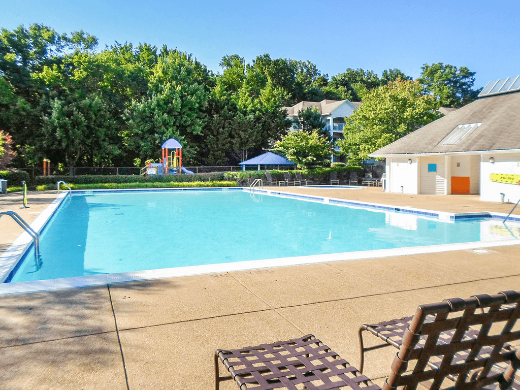 Pool area with tanning chairs on the deck facing leasing office and playground