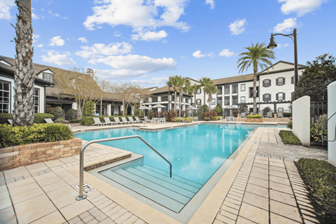 A swimming pool surrounded by a brick wall and a tiled walkway.