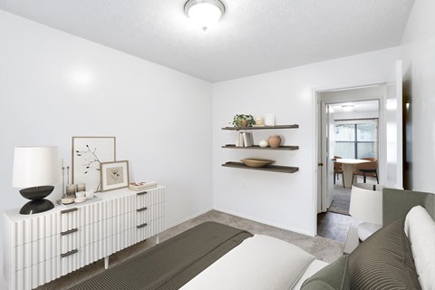 a bedroom with a bed and a dresser with a table in the background