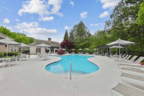 a swimming pool with chairs and umbrellas at the resort on a sunny day