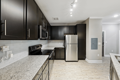 A kitchen with black cabinets and a stainless steel refrigerator.