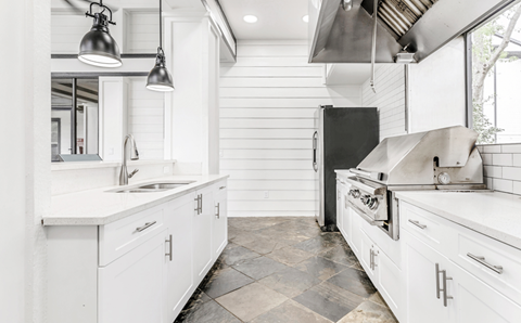 A modern kitchen with white cabinets and a black stove top oven.