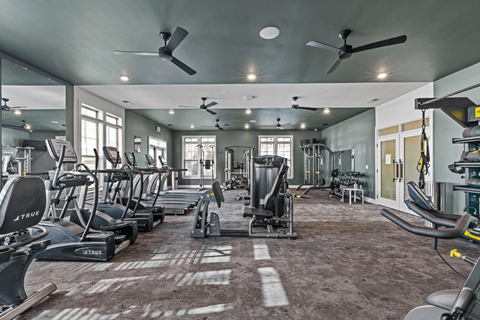 A gym with a variety of exercise equipment including treadmills, stationary bikes, and weight machines.