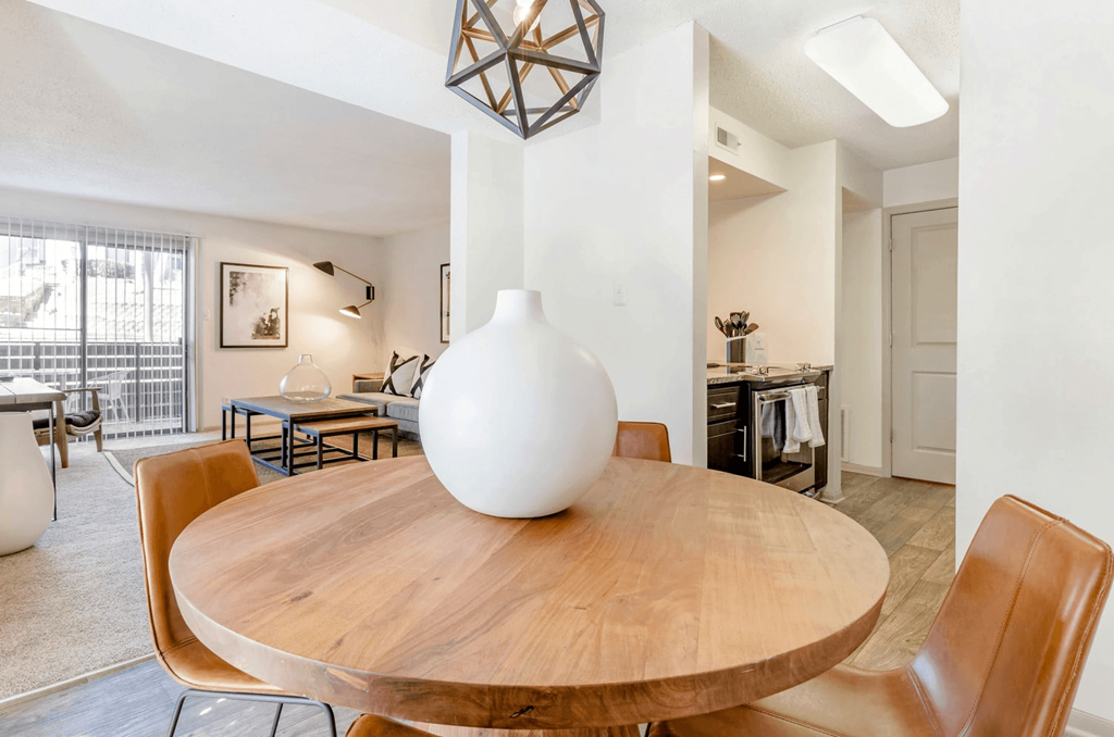 A white vase sits on a wooden table in a room with a brown chair at Madison Southpark Apartment Homes, North Carolina, 28226