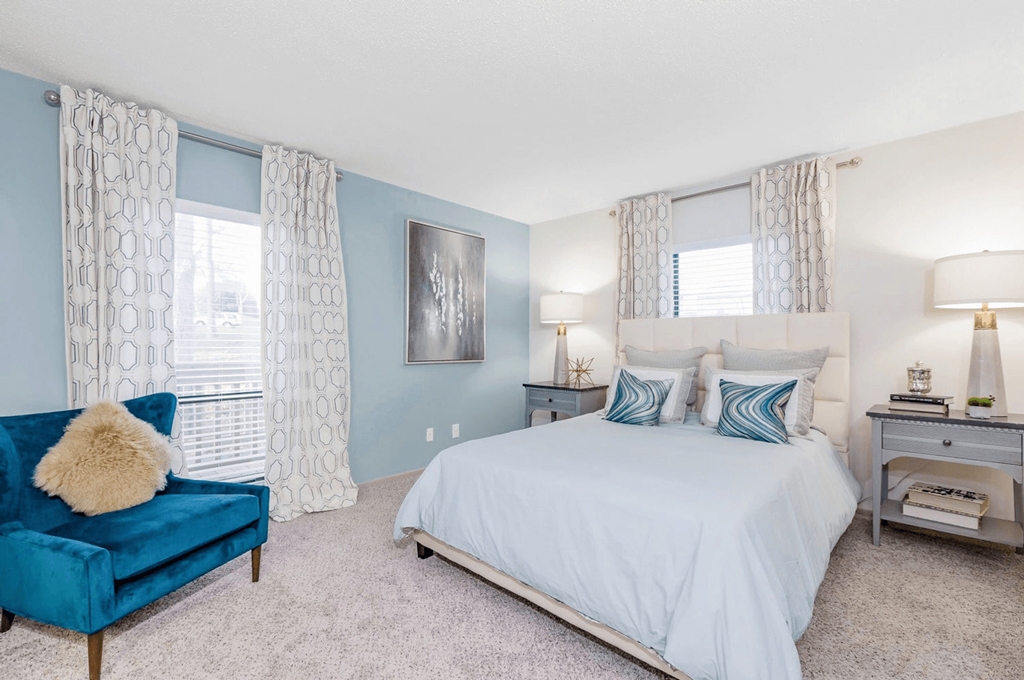 A bedroom with a blue couch and a white bed at Madison Southpark Apartment Homes, Charlotte, 28226