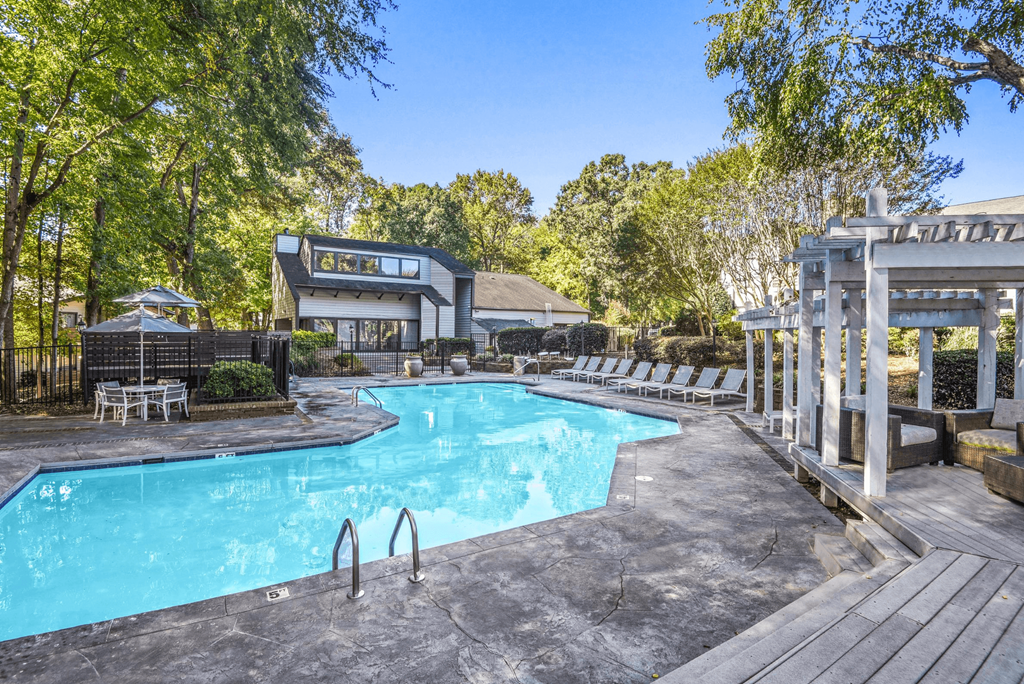 A large outdoor swimming pool surrounded by trees and a pavilion at Madison Southpark Apartment Homes, North Carolina