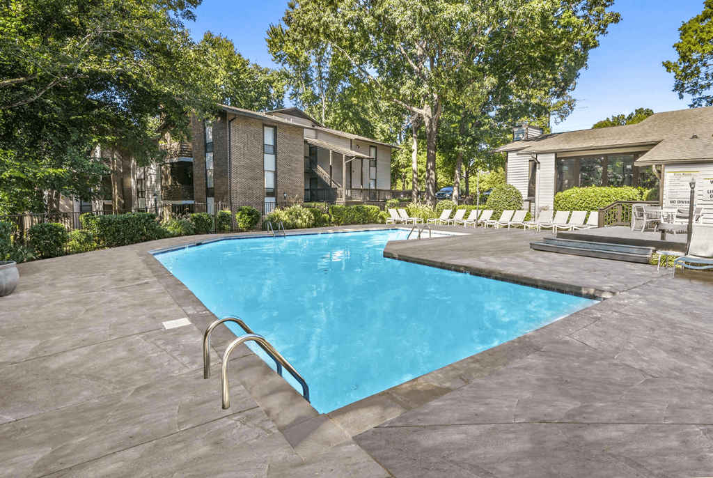 A swimming pool surrounded by a concrete patio and lounge chairs at Madison Southpark Apartment Homes, Charlotte, NC