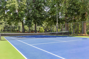 A blue tennis court surrounded by trees at Madison Southpark Apartment Homes, Charlotte, NC, 28226