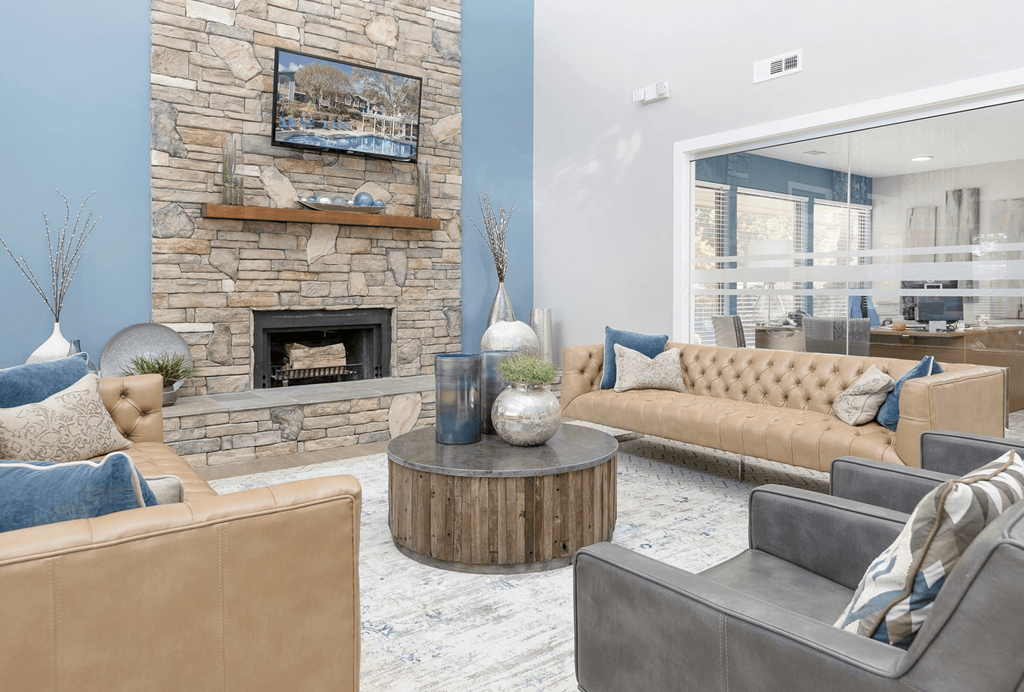 A living room with a stone fireplace and a painting above it at Madison Southpark Apartment Homes, North Carolina