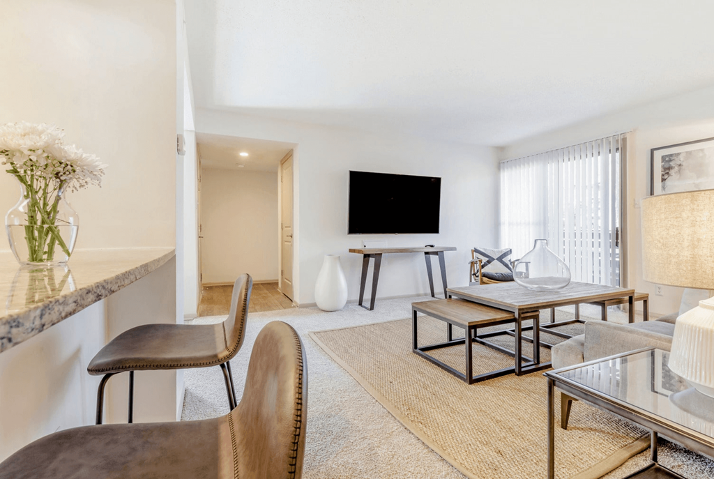 A living room with a flat screen TV, a glass coffee table, and a brown leather chair at Madison Southpark Apartment Homes, North Carolina, 28226