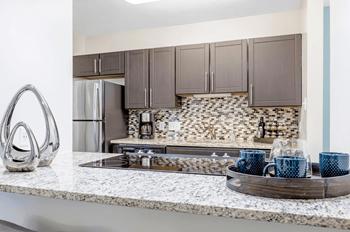 A kitchen with a marble countertop and a tray of blue mugs at Madison Southpark Apartment Homes, North Carolina