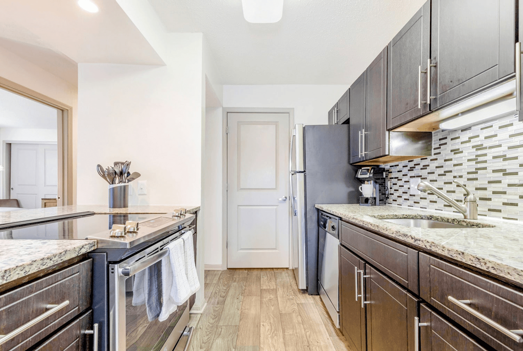 A kitchen with dark wood cabinets and granite countertops at Madison Southpark Apartment Homes, Charlotte, NC