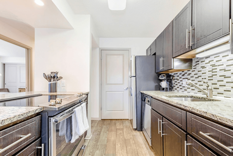 A kitchen with dark wood cabinets and granite countertops.