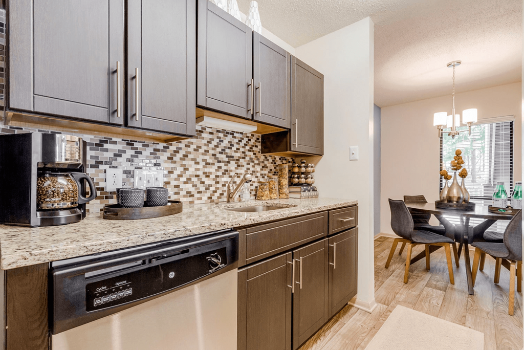 A kitchen with a black dishwasher and brown cabinets at Madison Southpark Apartment Homes, Charlotte, NC