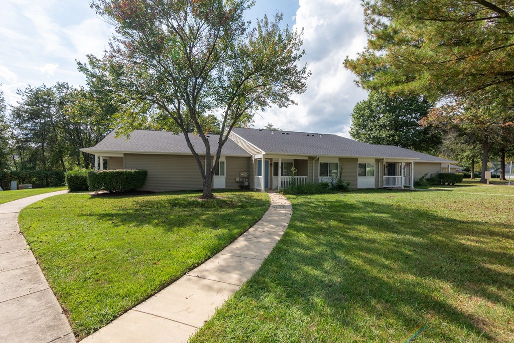 A house with a grey roof and a tree in front of it.