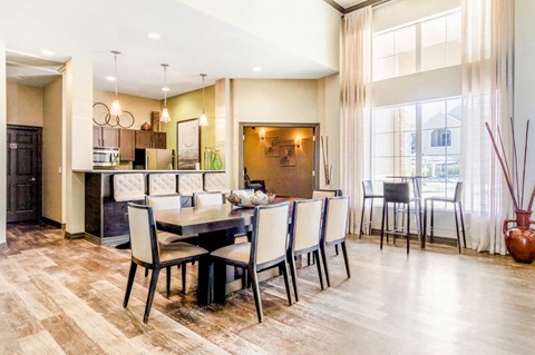 Clubhouse Kitchen with Long Dining Table and CHairs Next to Tall Windows